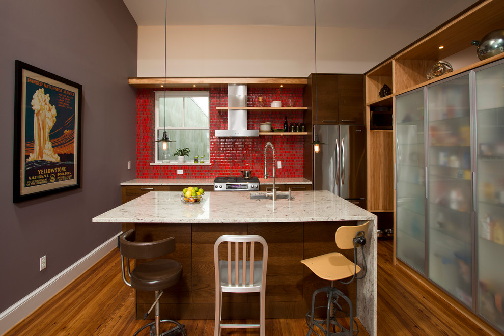 Example of a mid-sized trendy single-wall medium tone wood floor eat-in kitchen design in DC Metro with flat-panel cabinets, granite countertops, an undermount sink, dark wood cabinets, red backsplash, ceramic backsplash, stainless steel appliances and an island
