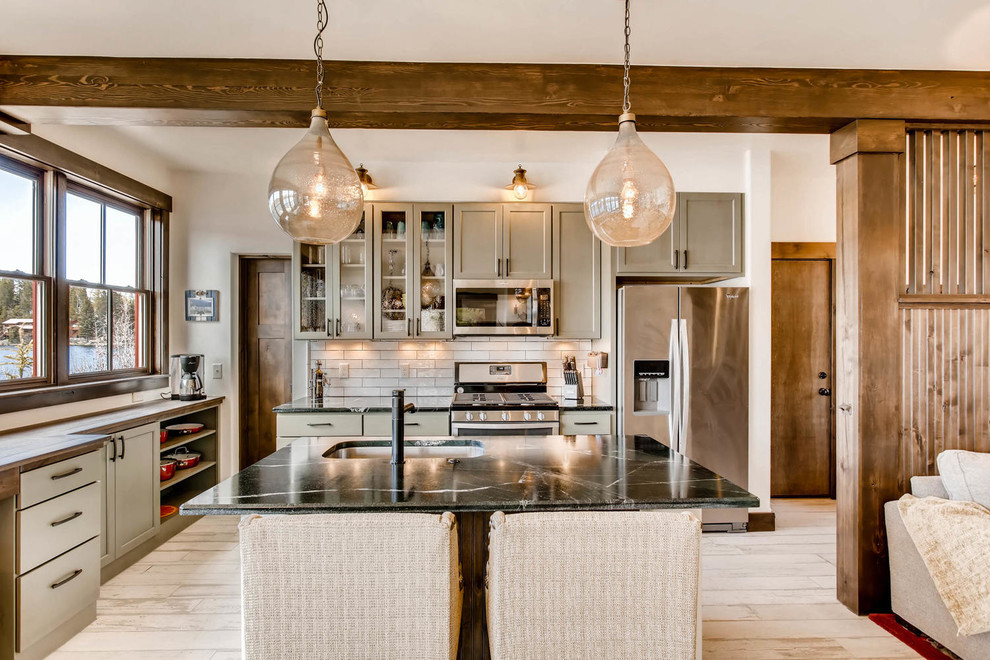 This is an example of a small rustic open plan kitchen in Denver with a single-bowl sink, shaker cabinets, green cabinets, soapstone worktops, white splashback, porcelain splashback, stainless steel appliances, porcelain flooring, an island and white floors.