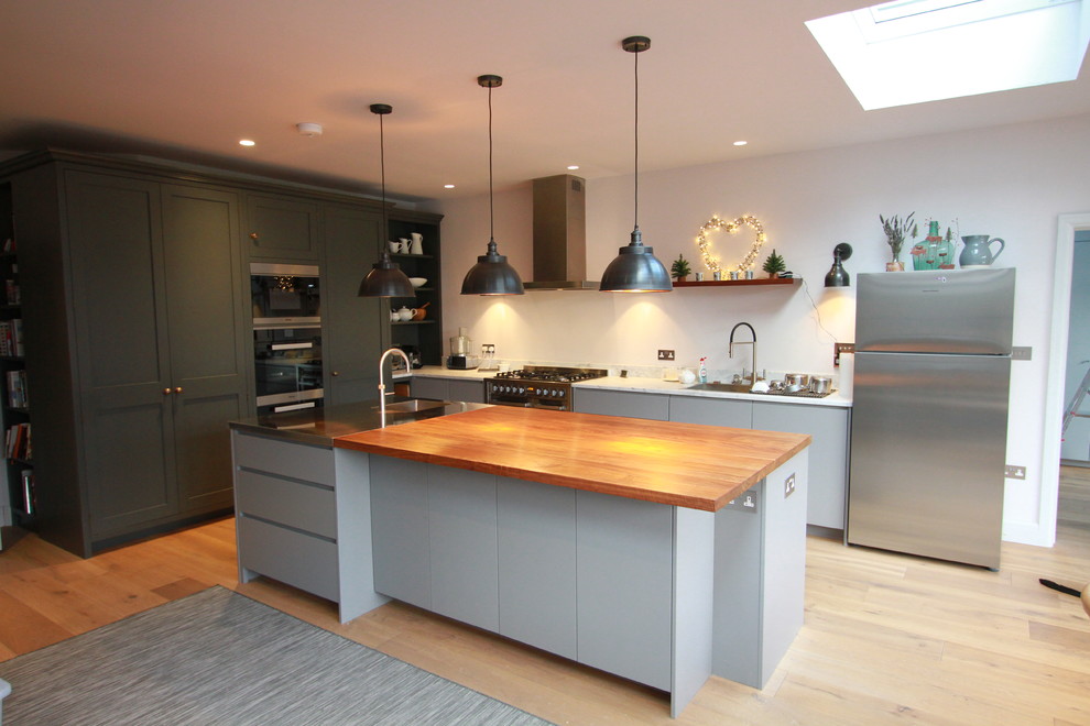 Klassische Wohnküche in L-Form mit Küchengeräten aus Edelstahl und Kücheninsel in London