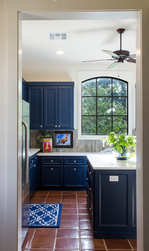 Inspiration for a medium sized country l-shaped enclosed kitchen in Austin with shaker cabinets, blue cabinets, composite countertops, grey splashback, porcelain splashback, stainless steel appliances, terracotta flooring and an island.