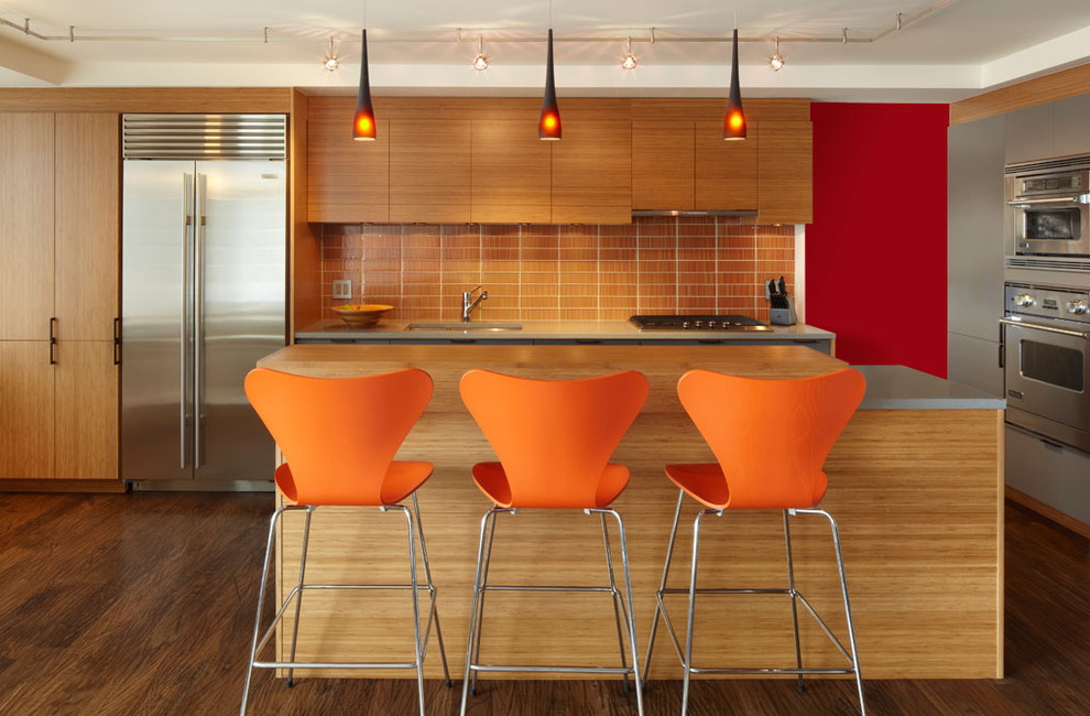 Kitchen - contemporary kitchen idea in New York with quartz countertops, stainless steel appliances, flat-panel cabinets, orange backsplash and glass tile backsplash