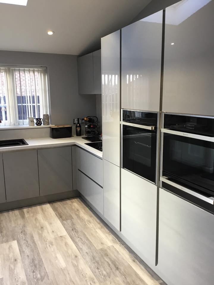 Medium sized contemporary u-shaped kitchen/diner in Other with a built-in sink, flat-panel cabinets, grey cabinets, laminate countertops, integrated appliances, vinyl flooring, a breakfast bar, grey floors and white worktops.