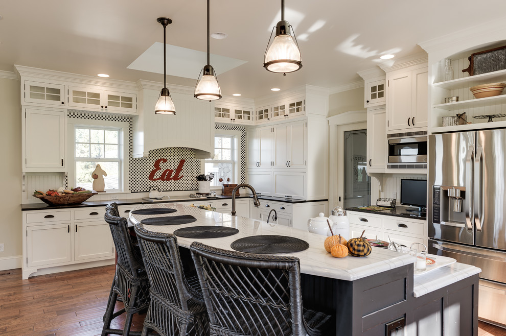 Example of a classic l-shaped dark wood floor kitchen design in Portland with shaker cabinets, white cabinets, stainless steel appliances and an island