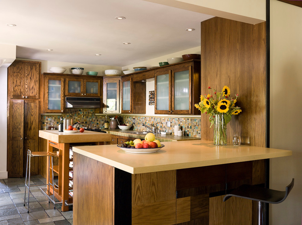 Foto di una cucina eclettica di medie dimensioni con lavello da incasso, ante di vetro, ante in legno bruno, paraspruzzi multicolore, paraspruzzi con piastrelle a mosaico, elettrodomestici in acciaio inossidabile e pavimento in travertino