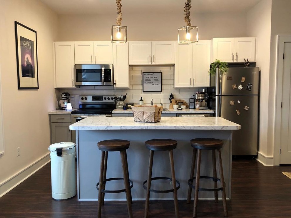 Exempel på ett litet modernt grå linjärt grått kök och matrum, med en undermonterad diskho, skåp i shakerstil, grå skåp, laminatbänkskiva, vitt stänkskydd, stänkskydd i tunnelbanekakel, rostfria vitvaror, mörkt trägolv, en köksö och blått golv