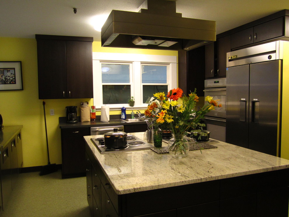 Modelo de cocina contemporánea con fregadero encastrado, armarios con paneles lisos, encimera de mármol, salpicadero negro y electrodomésticos de acero inoxidable