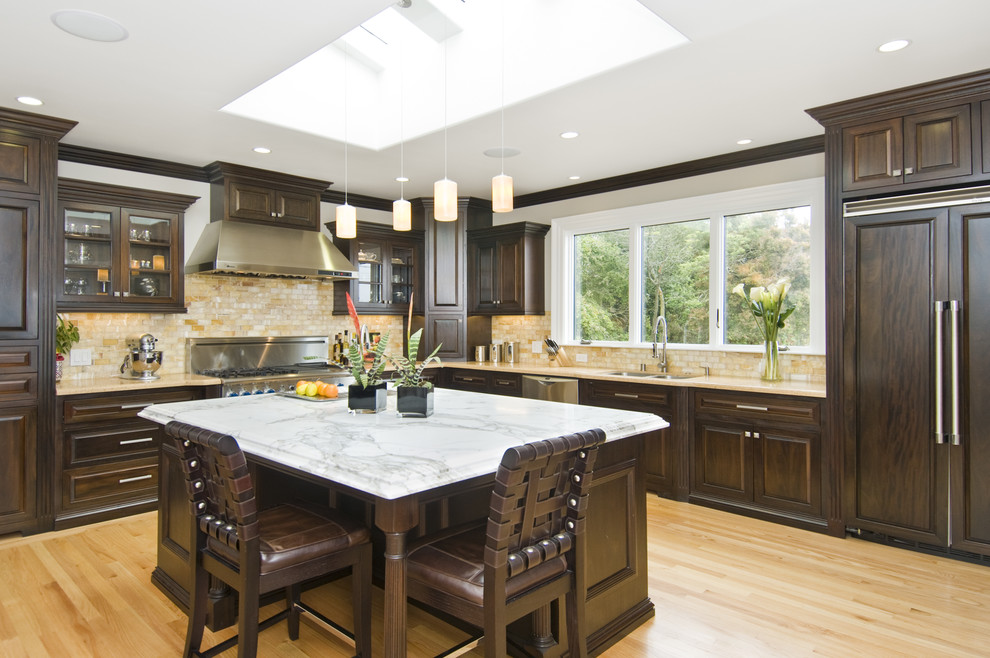 This is an example of a classic l-shaped kitchen in San Francisco with raised-panel cabinets, dark wood cabinets, beige splashback and integrated appliances.
