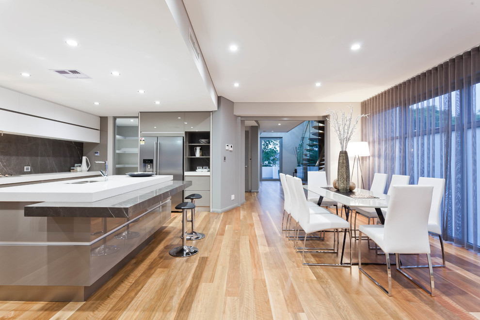This is an example of a contemporary kitchen/diner in Perth with a double-bowl sink, flat-panel cabinets, grey cabinets, grey splashback, stainless steel appliances, light hardwood flooring, an island and beige floors.