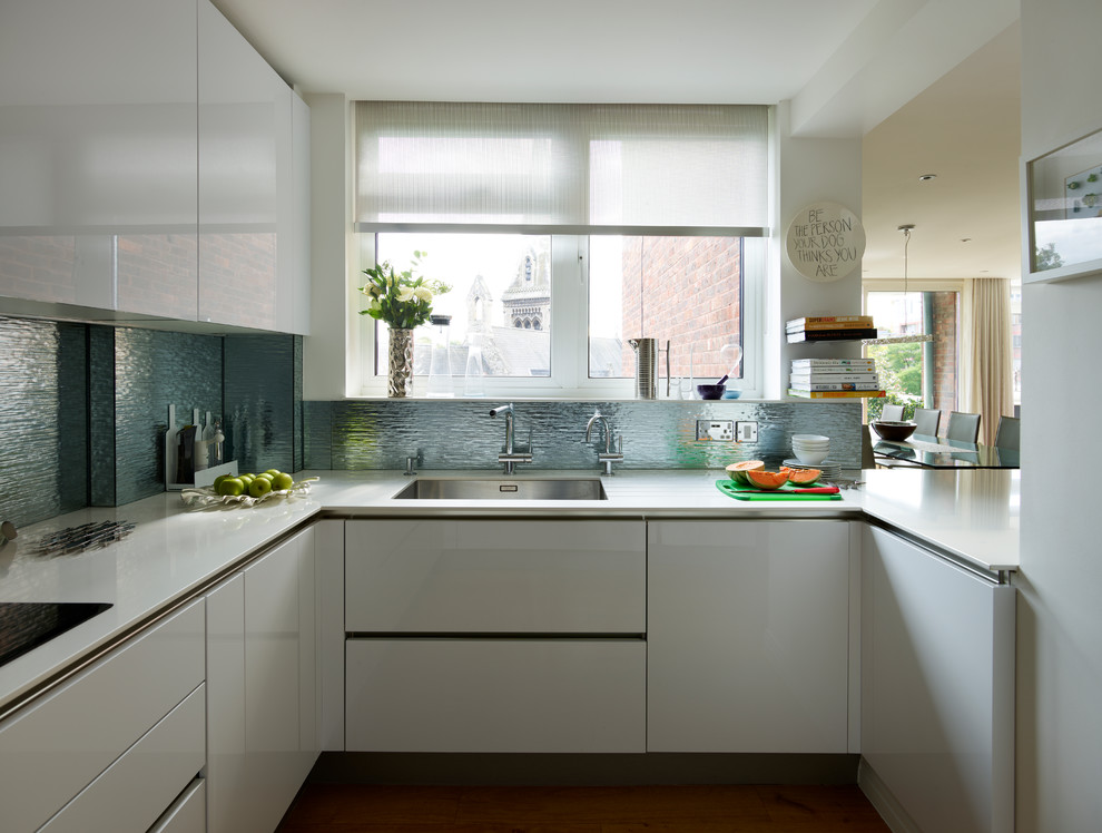 Diseño de cocina actual con armarios con paneles lisos, puertas de armario blancas, salpicadero azul y salpicadero de metal