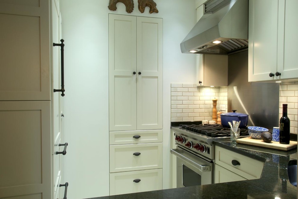 Medium sized classic u-shaped kitchen pantry in New York with a submerged sink, recessed-panel cabinets, white cabinets, composite countertops, white splashback, metro tiled splashback, stainless steel appliances and no island.
