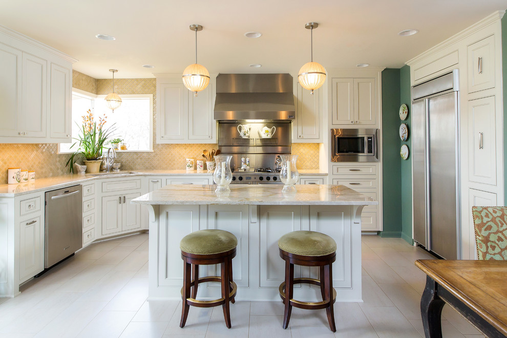 Klassisk inredning av ett kök och matrum, med en undermonterad diskho, luckor med profilerade fronter, vita skåp, beige stänkskydd, rostfria vitvaror, en köksö och beiget golv