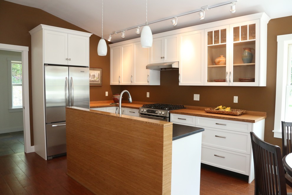 Eat-in kitchen - small contemporary galley medium tone wood floor and brown floor eat-in kitchen idea in Philadelphia with an undermount sink, recessed-panel cabinets, white cabinets, wood countertops, brown backsplash, stainless steel appliances and an island