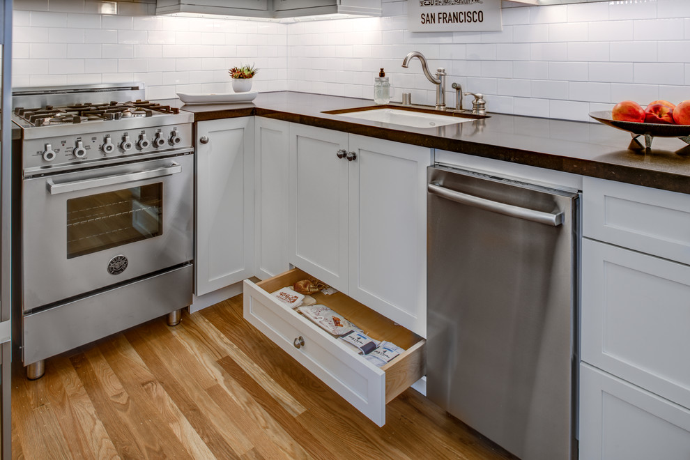 Small contemporary galley kitchen pantry in San Francisco with a submerged sink, shaker cabinets, white cabinets, engineered stone countertops, brown splashback, ceramic splashback, stainless steel appliances, light hardwood flooring and no island.