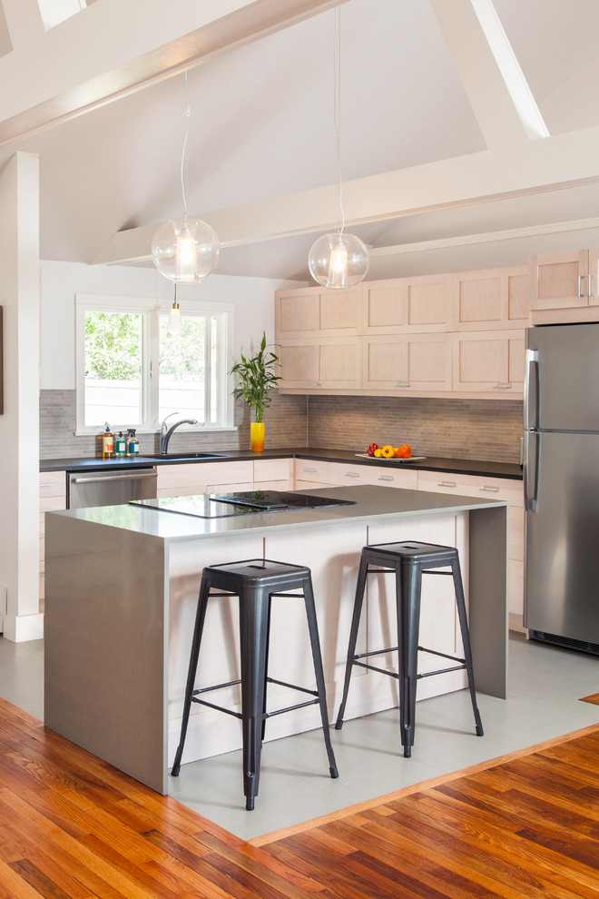 Modern inredning av ett litet kök, med en undermonterad diskho, skåp i shakerstil, grå skåp, bänkskiva i återvunnet glas, grått stänkskydd, stänkskydd i stickkakel, rostfria vitvaror, en köksö och betonggolv