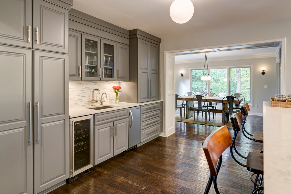 Example of a large trendy galley medium tone wood floor eat-in kitchen design in Los Angeles with a drop-in sink, raised-panel cabinets, gray cabinets, quartz countertops, white backsplash, stone tile backsplash, stainless steel appliances and a peninsula