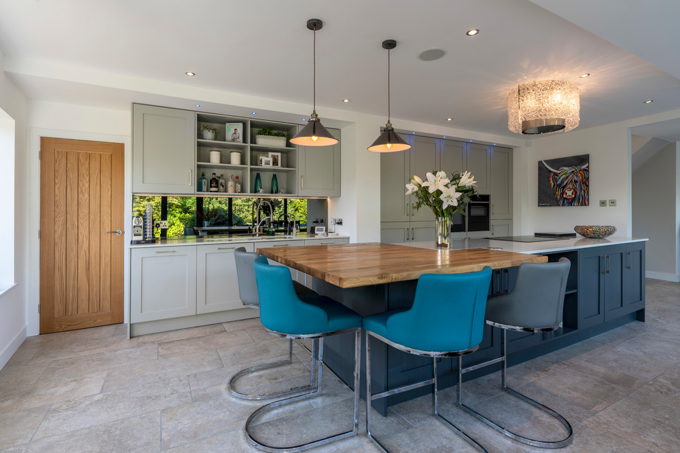 Immagine di un cucina con isola centrale chic con lavello sottopiano, ante in stile shaker, ante grigie, elettrodomestici neri, pavimento grigio e top bianco