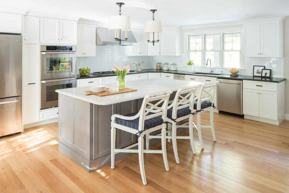 Inspiration for a large timeless u-shaped light wood floor eat-in kitchen remodel in Boston with an undermount sink, white cabinets, granite countertops, white backsplash, subway tile backsplash, stainless steel appliances, an island and shaker cabinets