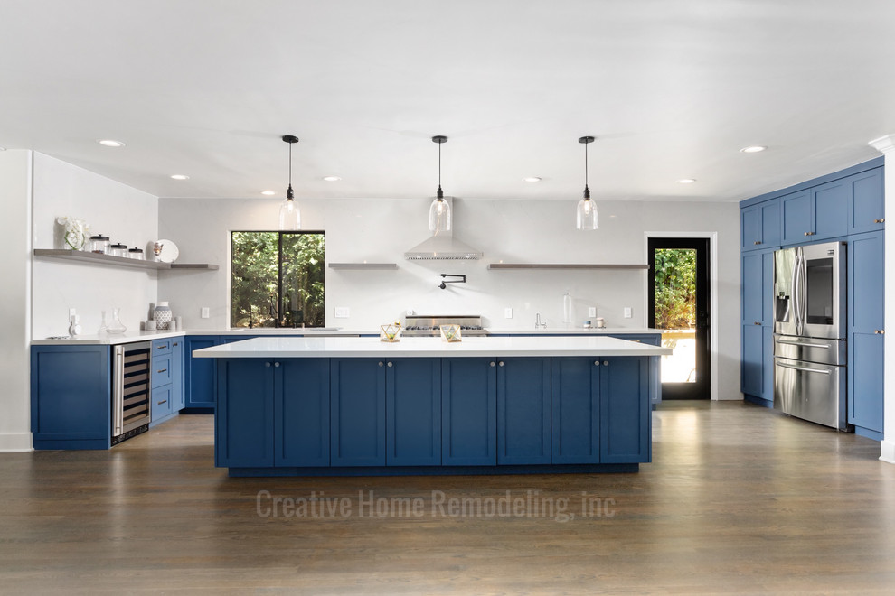Idee per una grande cucina minimal con lavello sottopiano, ante in stile shaker, ante blu, top in quarzite, elettrodomestici in acciaio inossidabile, parquet chiaro, pavimento marrone e top bianco