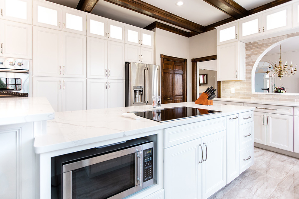 Inredning av ett modernt stort vit vitt kök, med en rustik diskho, luckor med upphöjd panel, vita skåp, bänkskiva i kvarts, beige stänkskydd, stänkskydd i travertin, rostfria vitvaror, klinkergolv i porslin, flera köksöar och beiget golv
