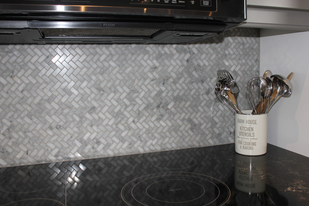 Esempio di una cucina classica di medie dimensioni con ante a filo, ante grigie, paraspruzzi con piastrelle a mosaico, elettrodomestici neri, pavimento in vinile, lavello sottopiano, paraspruzzi grigio, pavimento beige e top nero
