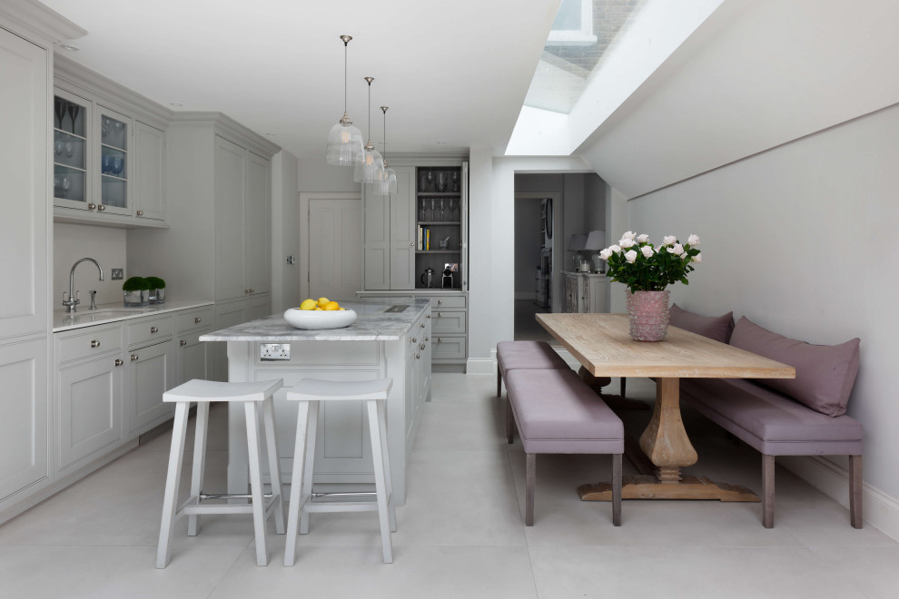 This is an example of a large classic l-shaped kitchen/diner in London with marble worktops, white splashback, limestone splashback, white appliances, an island, white worktops, a submerged sink, beaded cabinets, grey cabinets and grey floors.