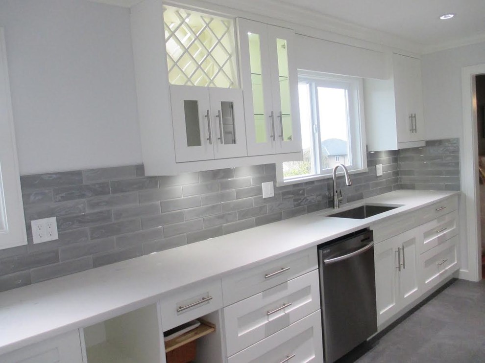 Enclosed kitchen - mid-sized transitional galley porcelain tile and gray floor enclosed kitchen idea in Vancouver with an undermount sink, shaker cabinets, white cabinets, solid surface countertops, gray backsplash, porcelain backsplash, stainless steel appliances and no island