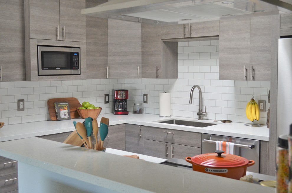 This is an example of a small modern l-shaped open plan kitchen in San Diego with a submerged sink, flat-panel cabinets, grey cabinets, quartz worktops, white splashback, metro tiled splashback, stainless steel appliances and an island.