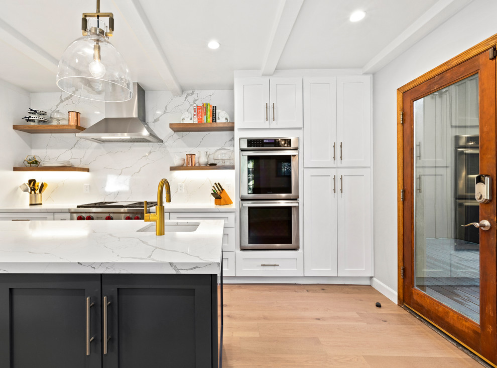 Photo of a large classic open plan kitchen in Los Angeles with shaker cabinets, engineered stone countertops, multi-coloured splashback, porcelain splashback, stainless steel appliances, light hardwood flooring, an island, beige floors and white worktops.