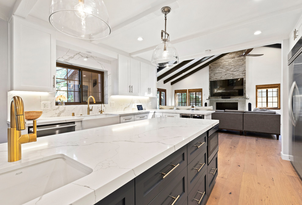 Photo of a large classic open plan kitchen in Los Angeles with shaker cabinets, engineered stone countertops, multi-coloured splashback, porcelain splashback, stainless steel appliances, light hardwood flooring, an island, beige floors and white worktops.