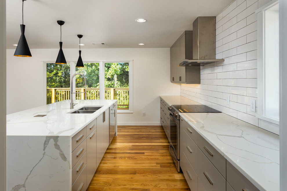 Idéer för att renovera ett mellanstort funkis kök, med en undermonterad diskho, släta luckor, grå skåp, marmorbänkskiva, vitt stänkskydd, stänkskydd i porslinskakel, rostfria vitvaror, mörkt trägolv och en köksö