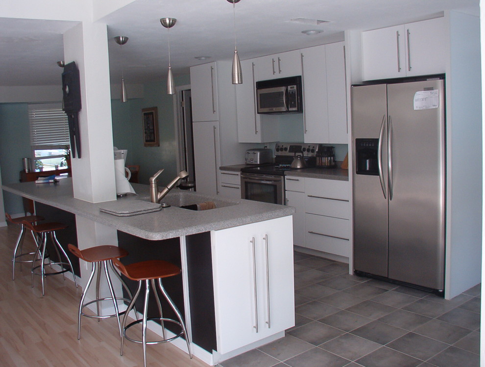 Bild på ett stort nordiskt grå linjärt grått kök och matrum, med en dubbel diskho, släta luckor, vita skåp, laminatbänkskiva, rostfria vitvaror, klinkergolv i keramik, en köksö och grått golv