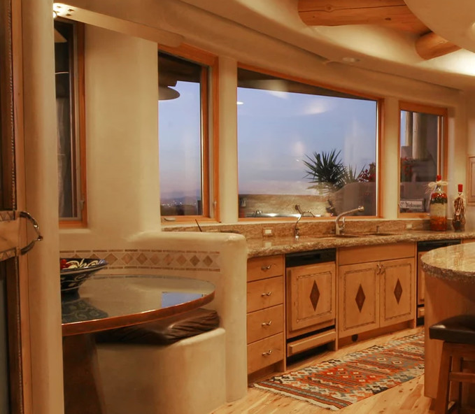 タンパにある高級な広い地中海スタイルのおしゃれなキッチン (ダブルシンク、フラットパネル扉のキャビネット、淡色木目調キャビネット、御影石カウンター、ベージュキッチンパネル、石スラブのキッチンパネル、シルバーの調理設備、淡色無垢フローリング、茶色い床、ベージュのキッチンカウンター) の写真