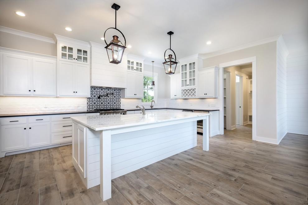 This is an example of a large nautical kitchen in New Orleans with light hardwood flooring and brown floors.