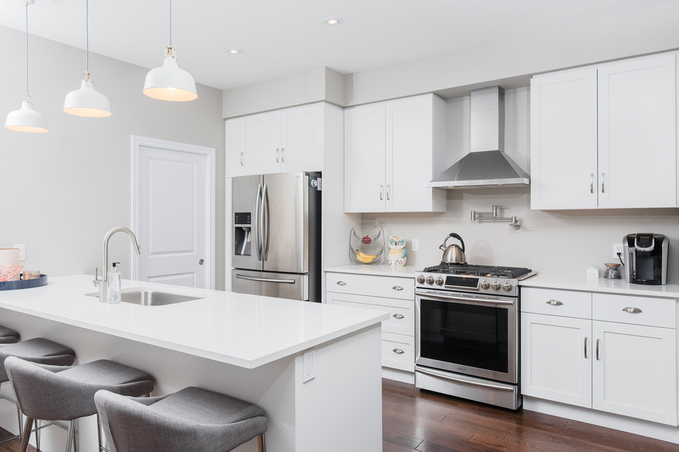 Eat-in kitchen - mid-sized transitional single-wall dark wood floor eat-in kitchen idea in Toronto with an undermount sink, shaker cabinets, white cabinets, quartz countertops, stainless steel appliances and an island