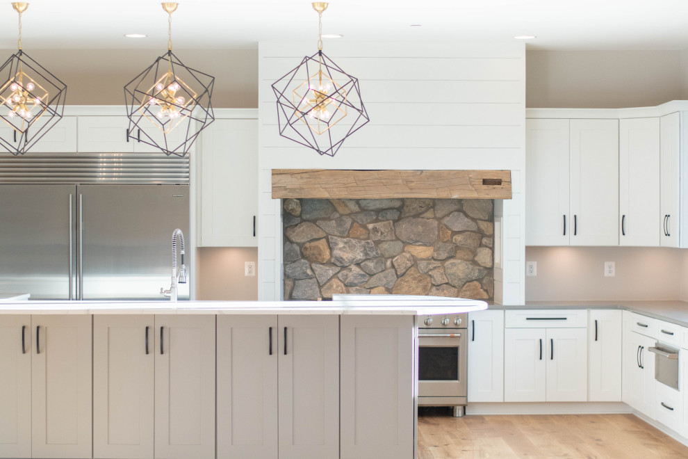 Immagine di una cucina country con ante bianche, elettrodomestici in acciaio inossidabile, parquet chiaro, pavimento marrone e top grigio