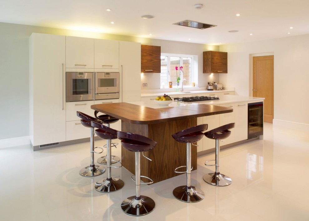 Foto på ett funkis parallellkök, med släta luckor, vita skåp, rostfria vitvaror och en köksö