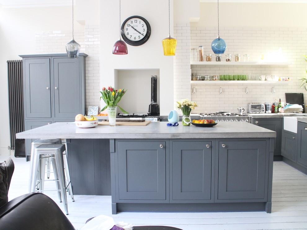Design ideas for a medium sized contemporary l-shaped kitchen in London with grey cabinets, concrete worktops, white splashback, metro tiled splashback, stainless steel appliances, light hardwood flooring, an island, white floors and shaker cabinets.