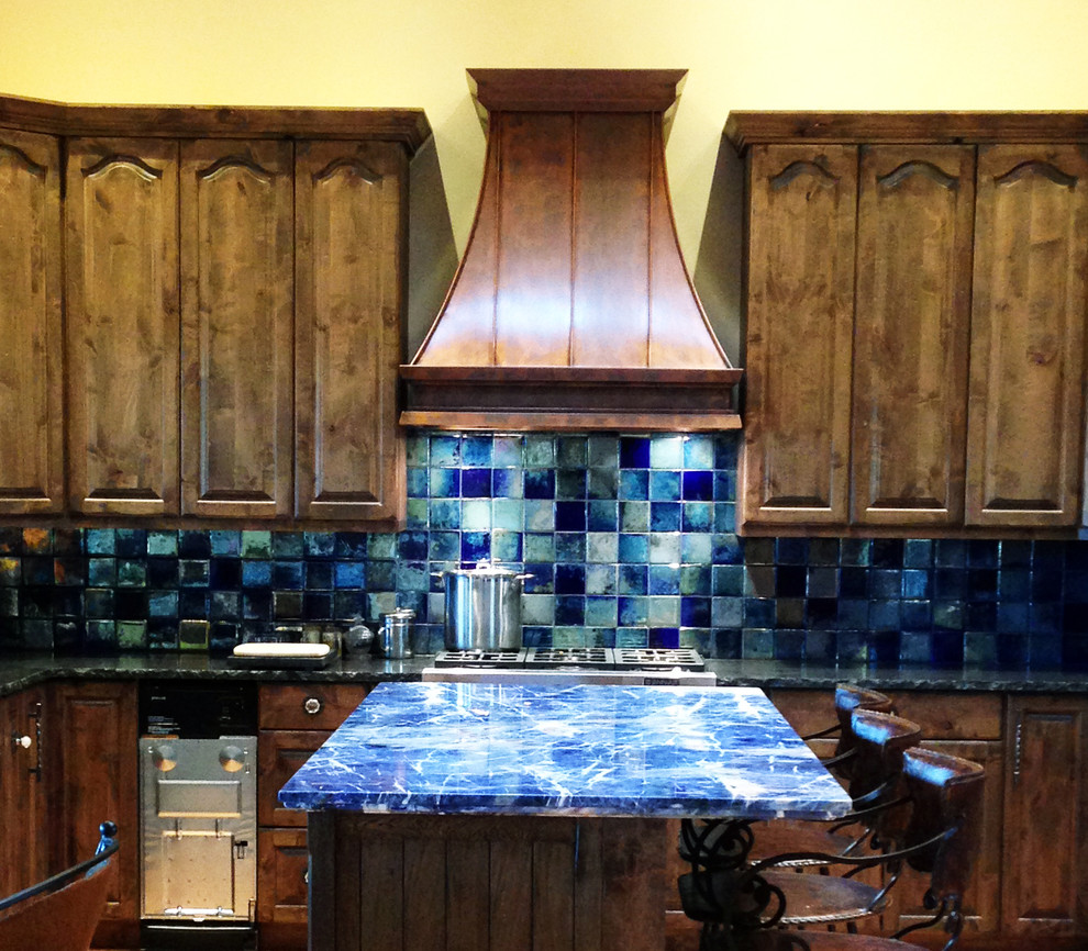 Inspiration for a mid-sized timeless l-shaped ceramic tile kitchen remodel in Austin with raised-panel cabinets, dark wood cabinets, onyx countertops, blue backsplash, porcelain backsplash, stainless steel appliances and an island