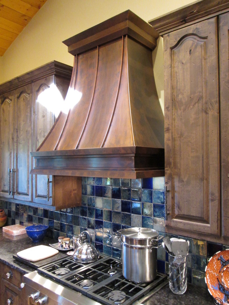 Bild på ett mellanstort vintage l-kök, med luckor med upphöjd panel, skåp i mörkt trä, bänkskiva i onyx, blått stänkskydd, stänkskydd i porslinskakel, rostfria vitvaror, klinkergolv i keramik och en köksö