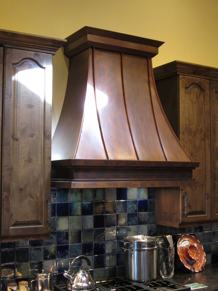 Inredning av ett klassiskt mellanstort l-kök, med luckor med upphöjd panel, skåp i mörkt trä, bänkskiva i onyx, blått stänkskydd, stänkskydd i porslinskakel, rostfria vitvaror, klinkergolv i keramik och en köksö