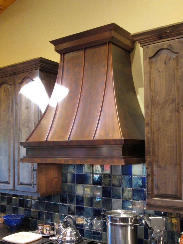 Inspiration for a mid-sized timeless l-shaped ceramic tile kitchen remodel in Austin with raised-panel cabinets, dark wood cabinets, onyx countertops, blue backsplash, porcelain backsplash, stainless steel appliances and an island