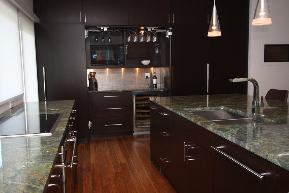 Example of a trendy bamboo floor kitchen design in Cleveland with a double-bowl sink, flat-panel cabinets, dark wood cabinets, granite countertops, metallic backsplash, metal backsplash, paneled appliances and an island
