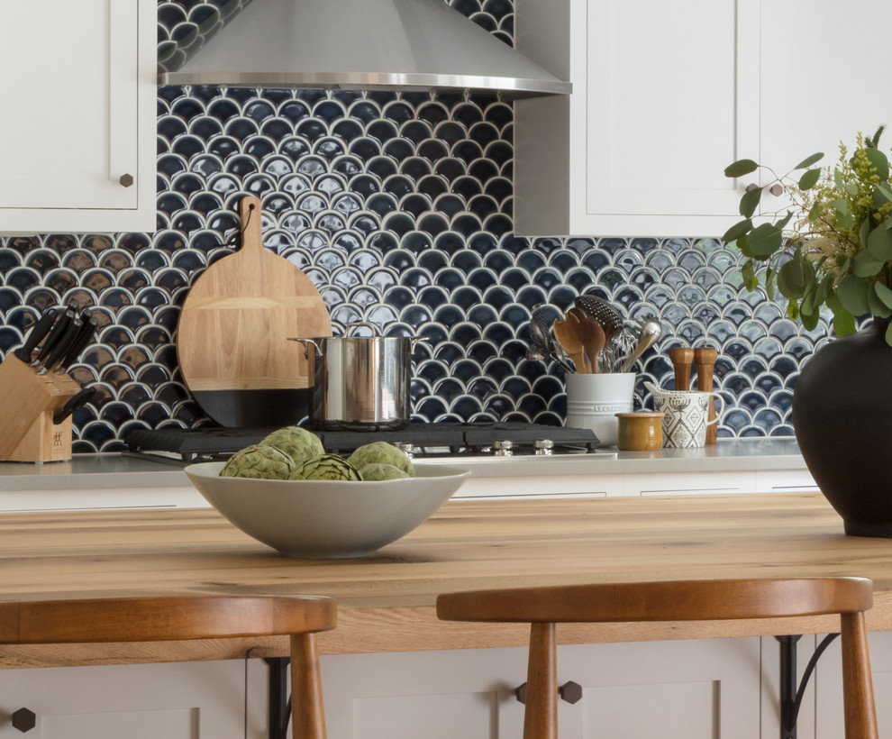 Beach style light wood floor kitchen photo in Boston with a farmhouse sink, shaker cabinets, white cabinets, wood countertops, blue backsplash and ceramic backsplash