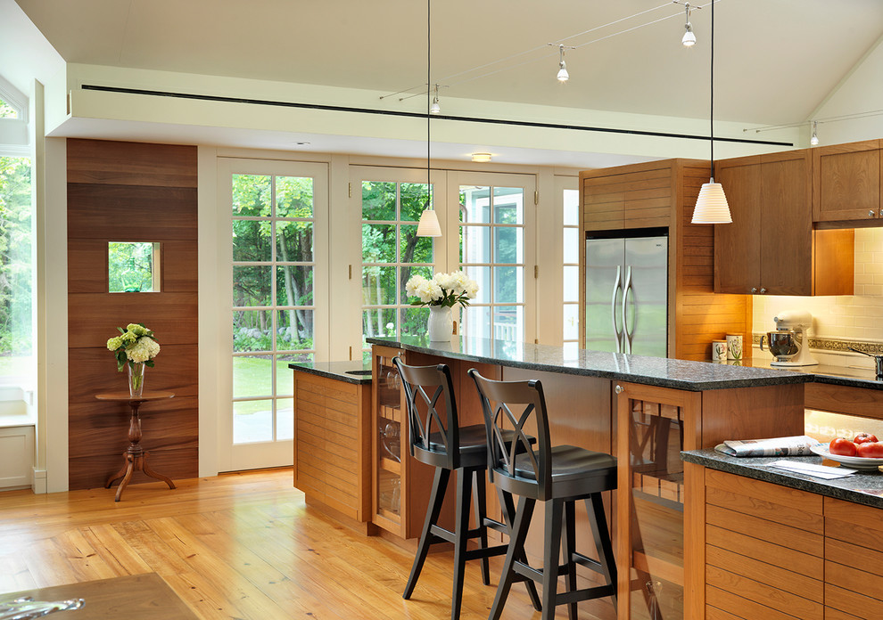 Example of a transitional galley open concept kitchen design in Boston with recessed-panel cabinets, medium tone wood cabinets, white backsplash and stainless steel appliances
