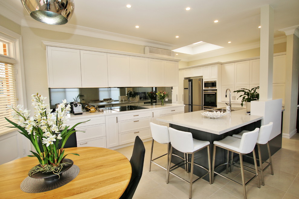Design ideas for a large classic l-shaped kitchen/diner in Sydney with a built-in sink, shaker cabinets, white cabinets, engineered stone countertops, grey splashback, glass sheet splashback, stainless steel appliances, ceramic flooring and an island.