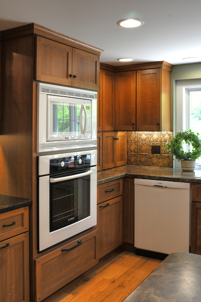 Foto på ett mellanstort vintage kök, med en dubbel diskho, luckor med glaspanel, bruna skåp, laminatbänkskiva, brunt stänkskydd, vita vitvaror, stänkskydd i metallkakel, mellanmörkt trägolv och brunt golv