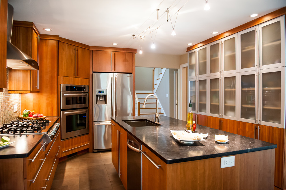 Medium sized modern l-shaped kitchen/diner in Boston with stainless steel appliances, a submerged sink, flat-panel cabinets, medium wood cabinets, granite worktops, multi-coloured splashback, glass tiled splashback, porcelain flooring and an island.