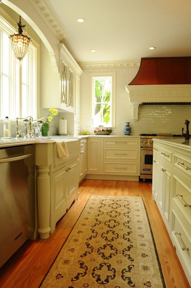Exempel på ett stort klassiskt kök och matrum, med en rustik diskho, luckor med profilerade fronter, vita skåp, marmorbänkskiva, stänkskydd i tunnelbanekakel, rostfria vitvaror, vitt stänkskydd, ljust trägolv och en köksö