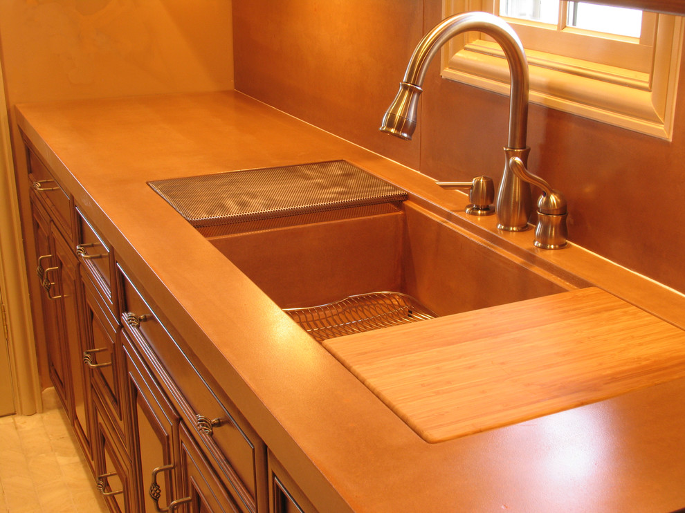 Cette photo montre une cuisine américaine chic en L et bois brun de taille moyenne avec un évier intégré, un placard avec porte à panneau surélevé, un plan de travail en béton et une crédence en carreau de ciment.
