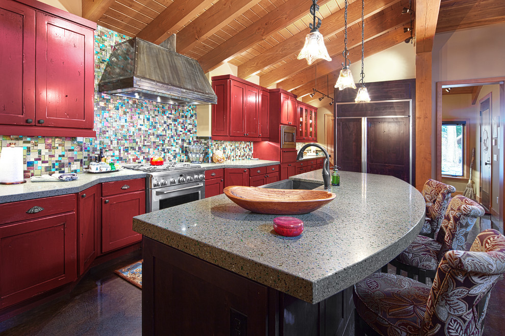 Modelo de cocina rústica de obra con puertas de armario rojas, armarios con paneles empotrados, salpicadero multicolor, salpicadero con mosaicos de azulejos y electrodomésticos con paneles